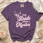 Purple t-shirt with pink "This Bride Needs a Martini" graphic and martini glass.