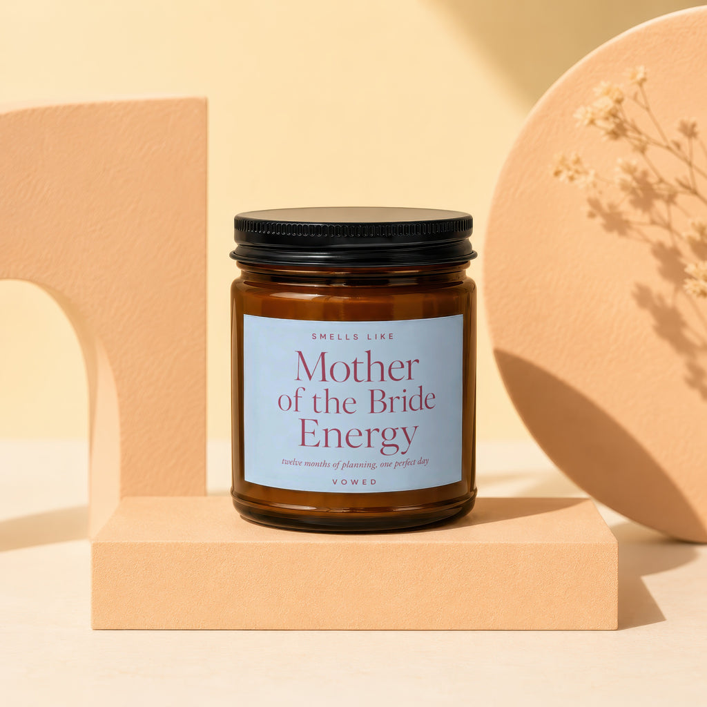 Brown glass candle labeled "Mother of the Bride Energy" with "VOWED" at the bottom.