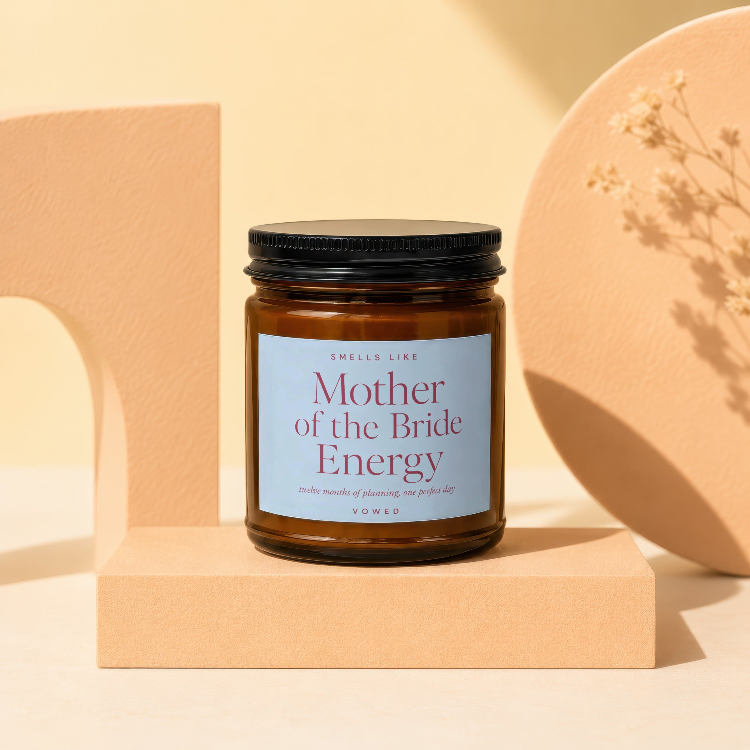Brown glass candle labeled "Mother of the Bride Energy" with "VOWED" at the bottom.
