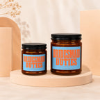 Two brown glass candles with blue labels reading "BRIDESMAID DUTIES (LOADING...) VOWED".