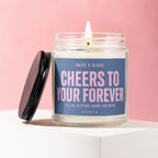 Lit candle with blue label reading "Cheers to Your Forever" and "Vowed".
