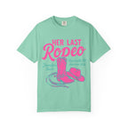 Mint t-shirt with pink "Her Last Rodeo" text, cowboy boots, and hat.