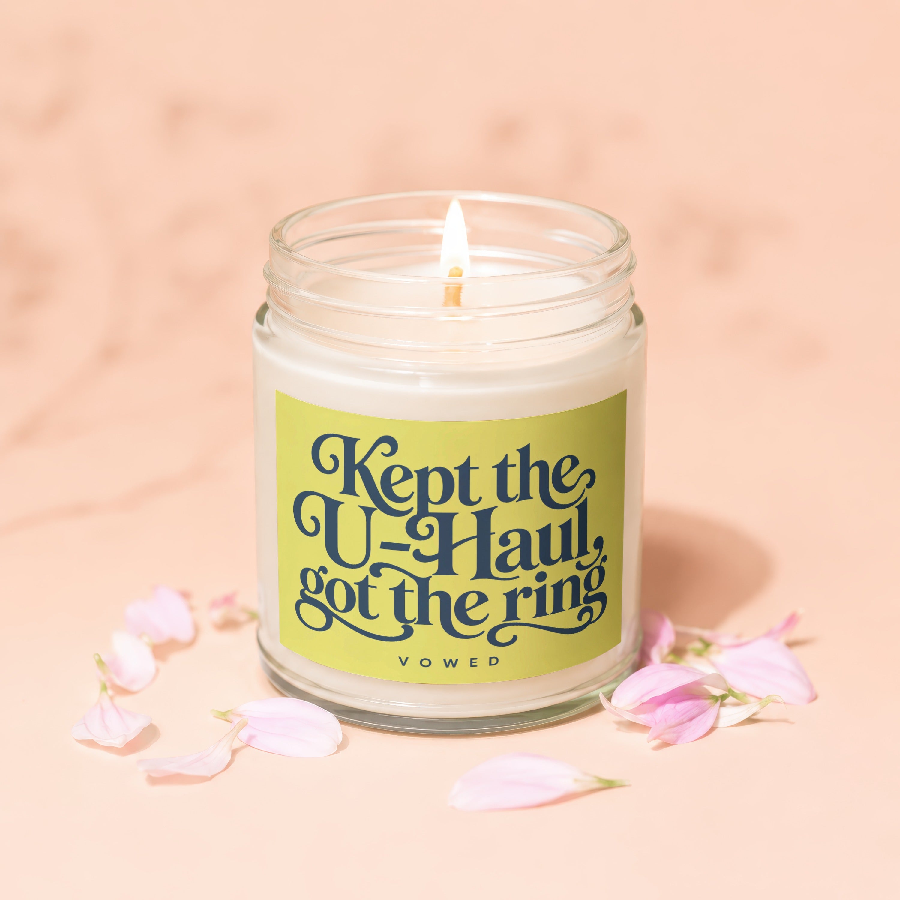 Candle with text "Kept the U-Haul, got the ring" surrounded by pink petals.