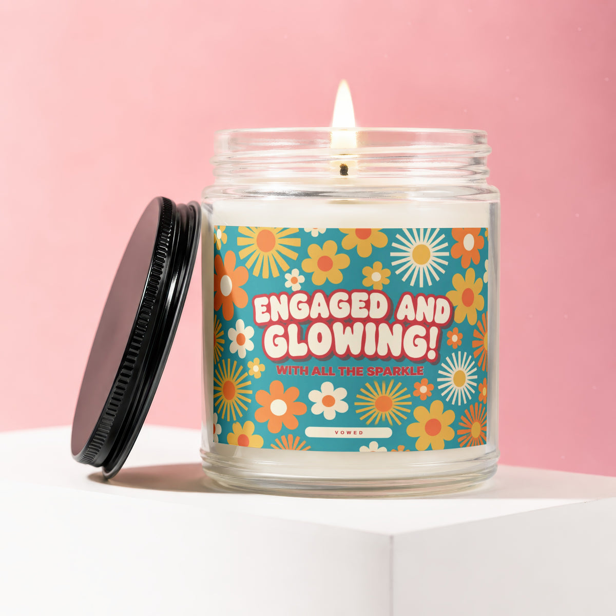 Glass candle with retro flower label reading "ENGAGED AND GLOWING! WITH ALL THE SPARKLE"