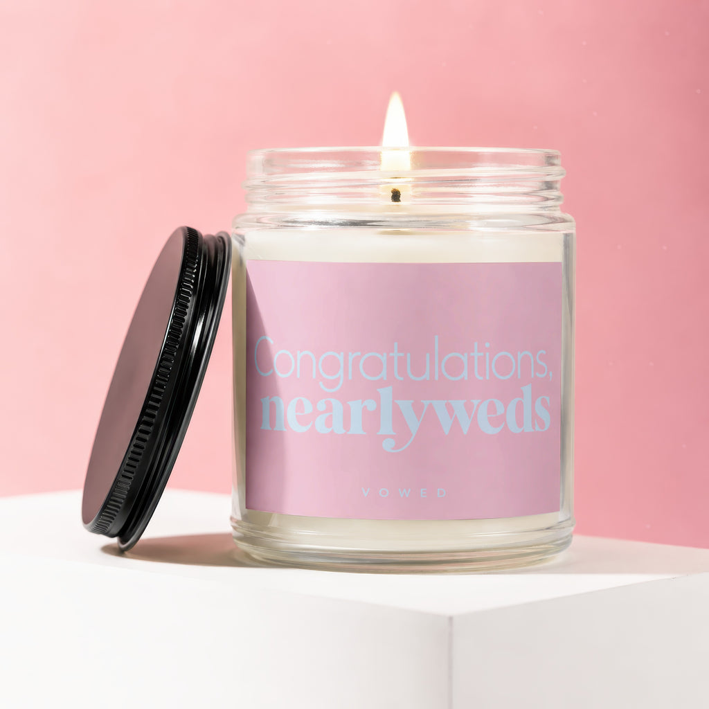 Candle with pink label reading "Congratulations, nearlyweds" and "vowed" on pink background.