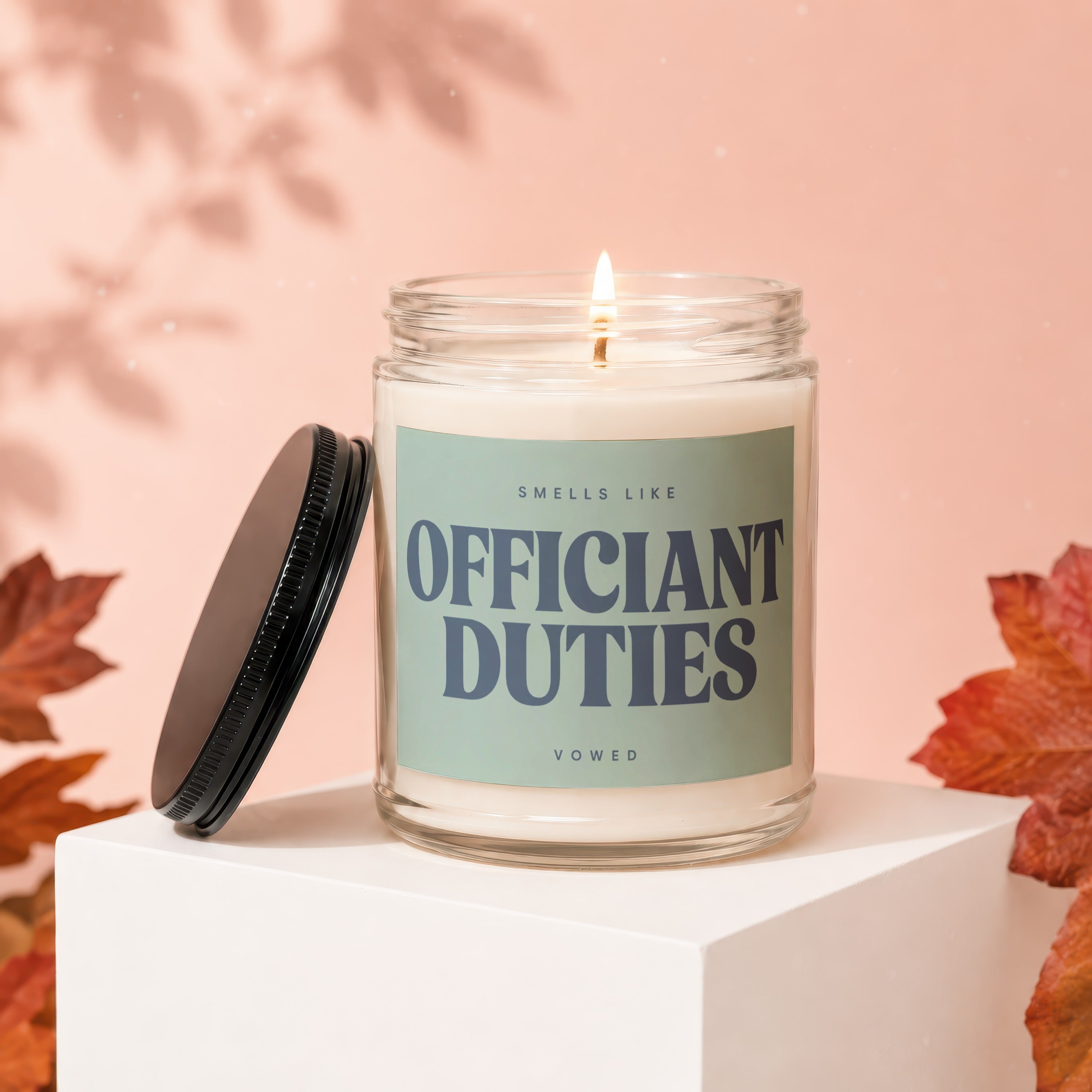 Candle with "Smells Like Officiant Duties Vowed" label on a white pedestal.