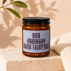 Amber jar candle with label reading "our ordinary dark fairytale"