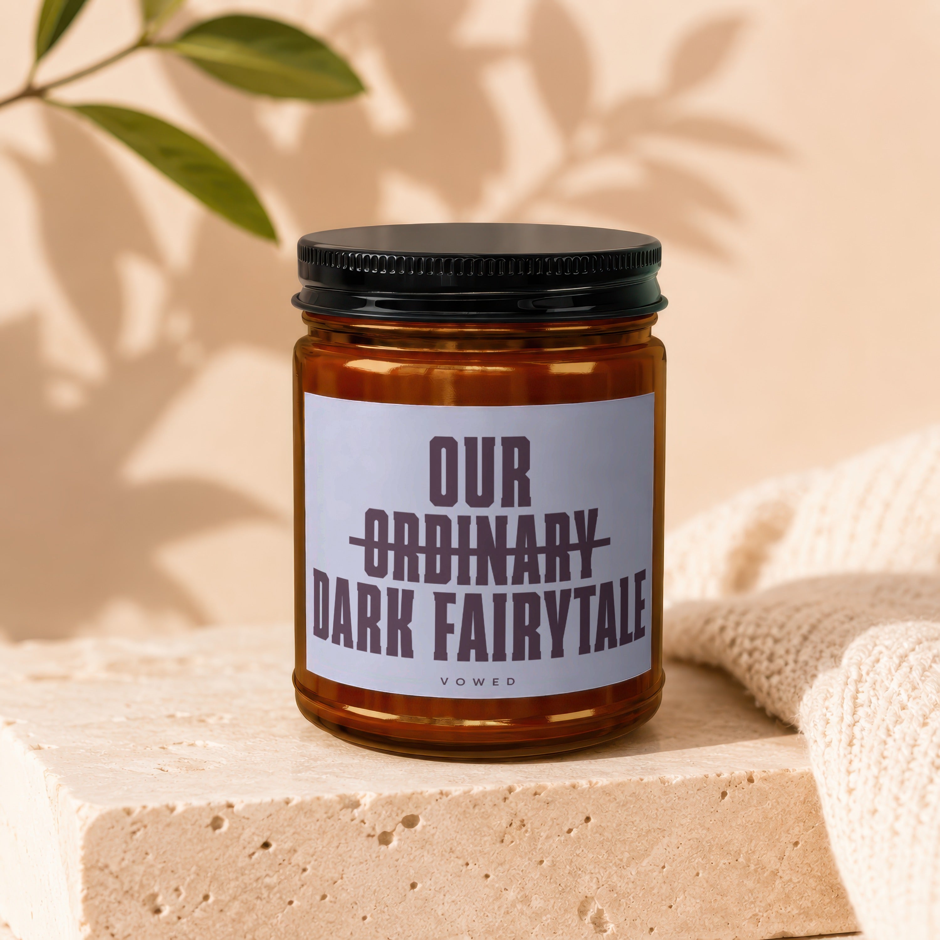 Amber jar candle with label reading "our ordinary dark fairytale"