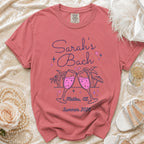 Coral t-shirt for "Sarah's Bach Malibu, Ca Summer 2026" with champagne glasses.