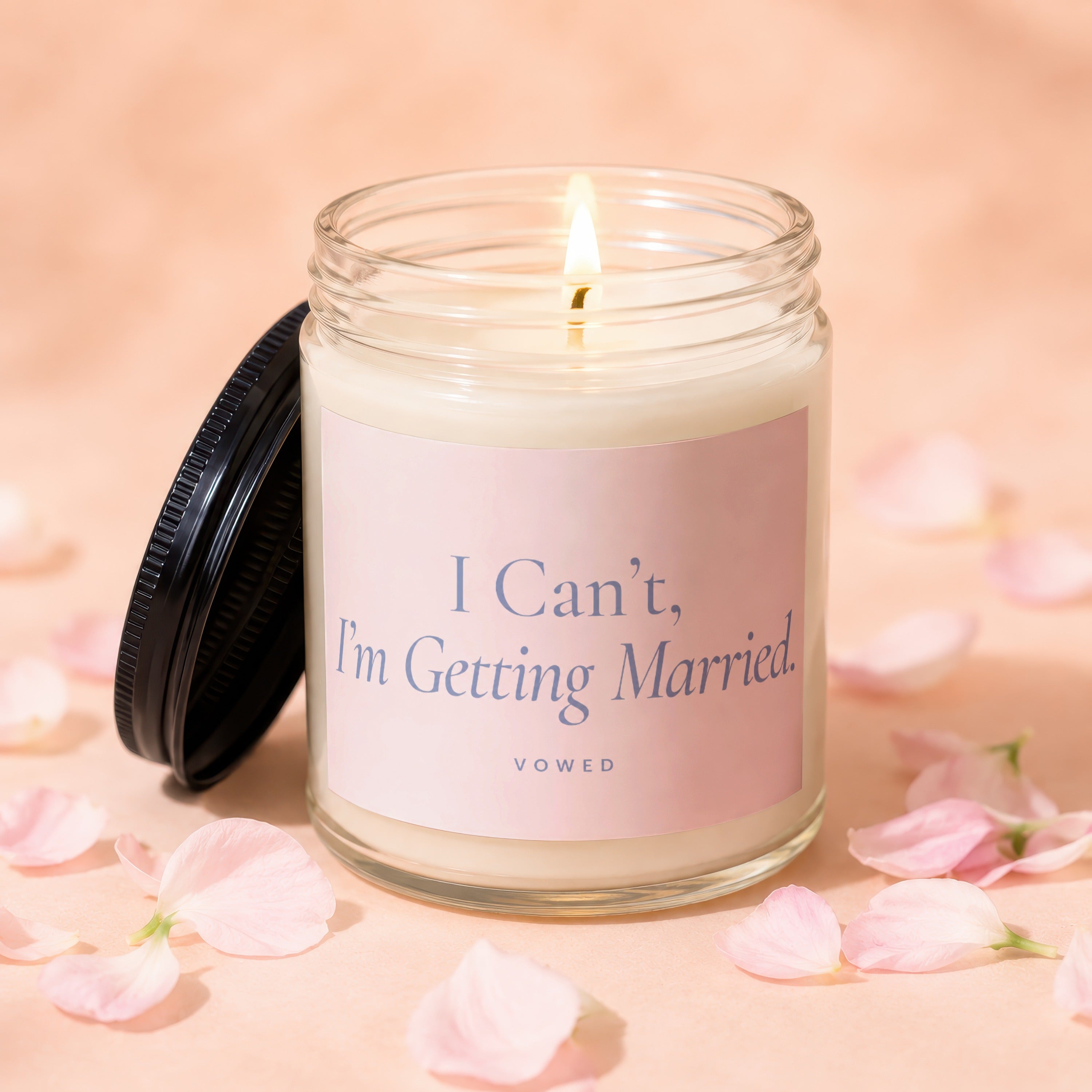 Glass candle with lit wick and pink label reading "I Can't, I'm Getting Married."