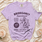 Purple t-shirt with "Bridegancy Department" graphic, skeleton bride, and "1-800-BRIDE-HELP" phone number.