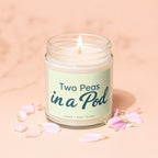 Candle labeled "Two Peas in a Pod" with lit wick and pink petals.