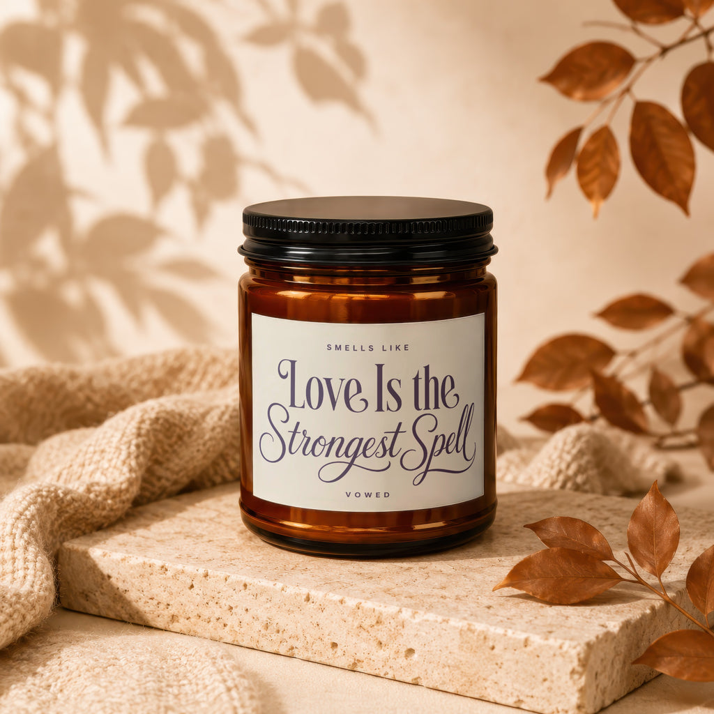 Amber candle with black lid, label reads "Love Is the Strongest Spell".
