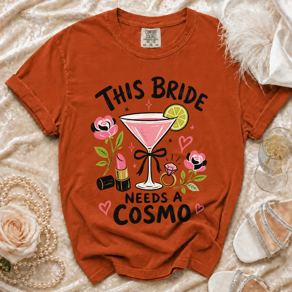 Orange t-shirt with "This Bride Needs a Cosmo" graphic featuring a cocktail, lipstick, and ring.