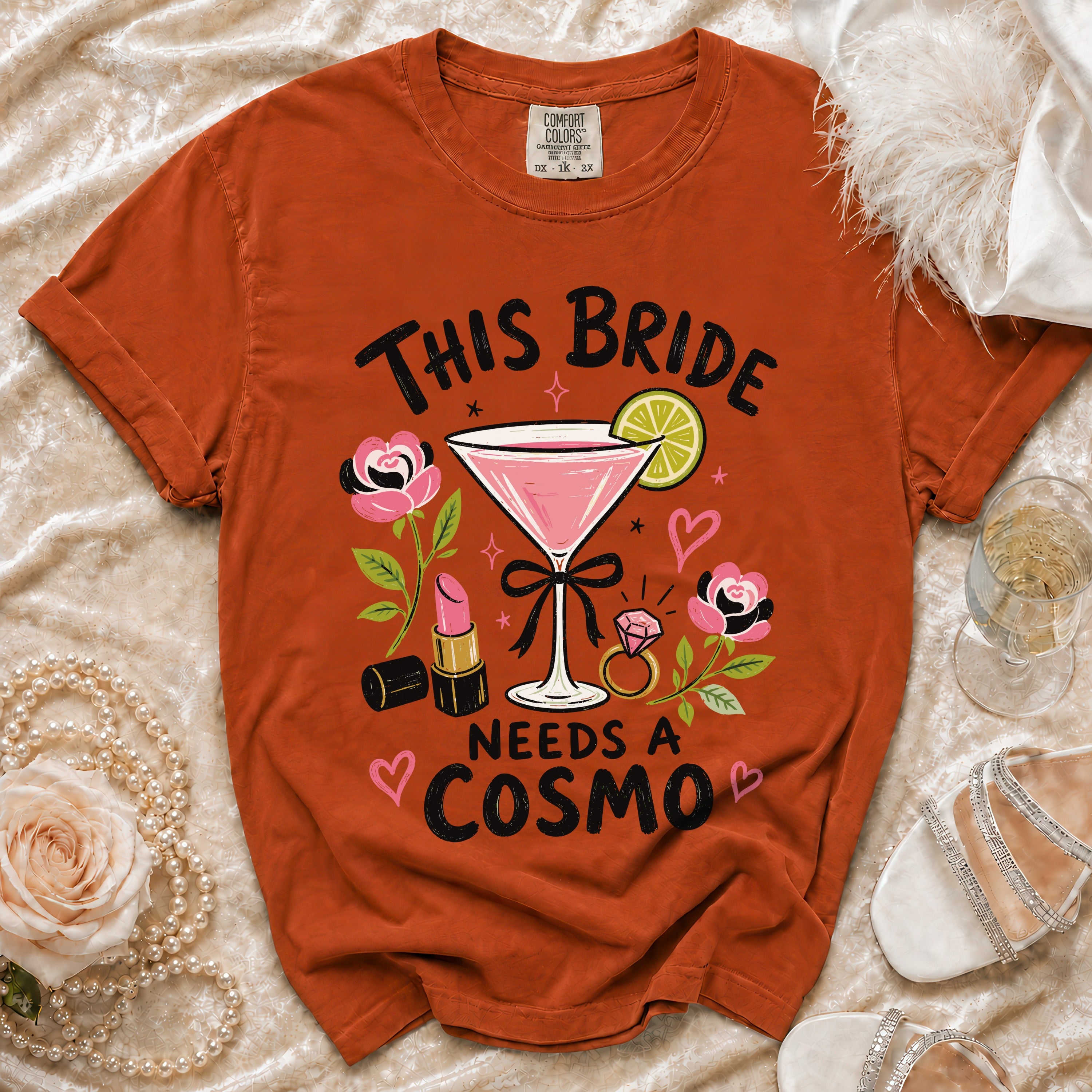 Orange t-shirt with "This Bride Needs a Cosmo" graphic featuring a cocktail, lipstick, and ring.