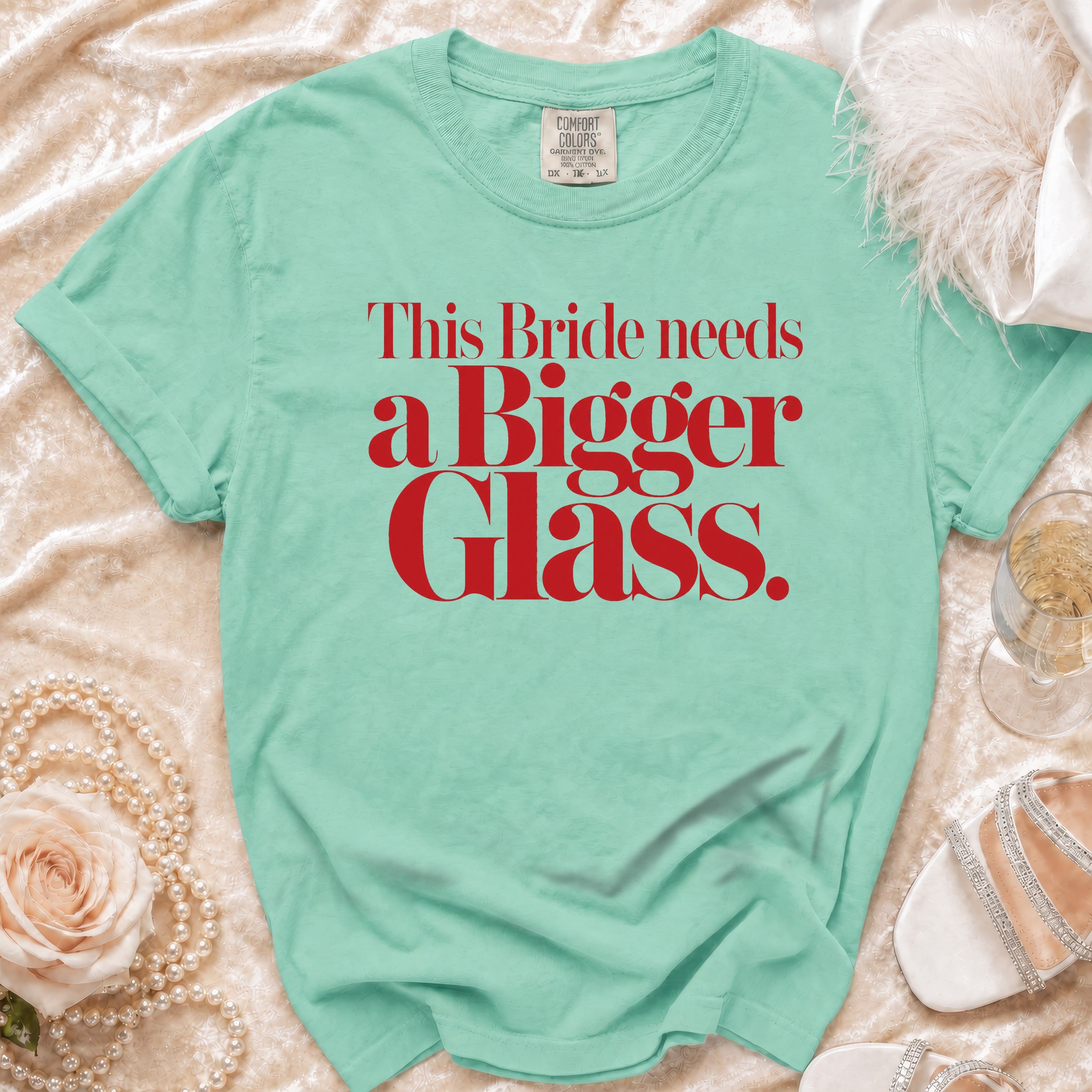 Mint green t-shirt with red text: "This Bride needs a Bigger Glass."