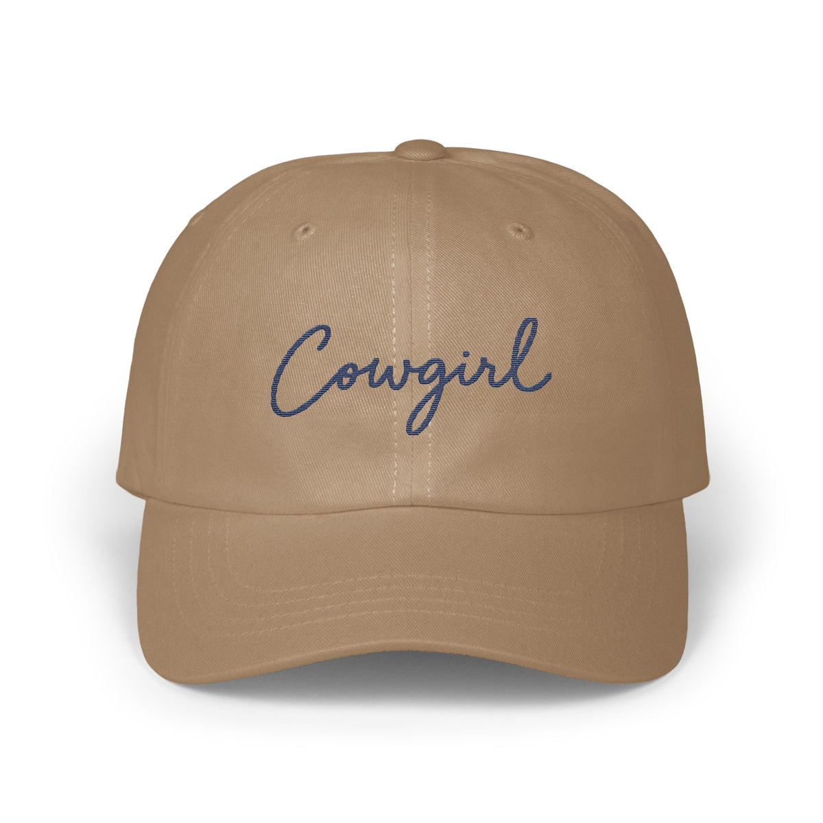 A tan baseball cap with the word Cowgirl embroidered in blue cursive on the front.