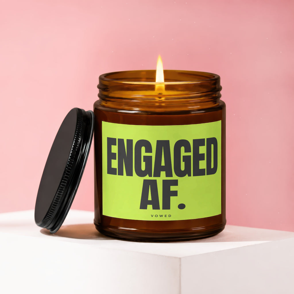 Lit amber glass candle with lid off, reads "ENGAGED AF."