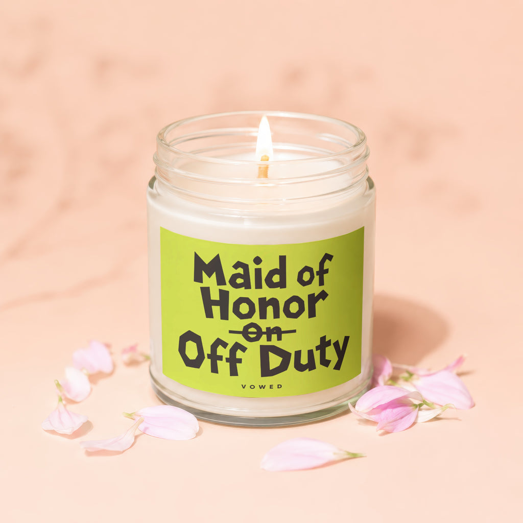 Lit candle in glass jar with "Maid of Honor on Off Duty" text and pink petals.