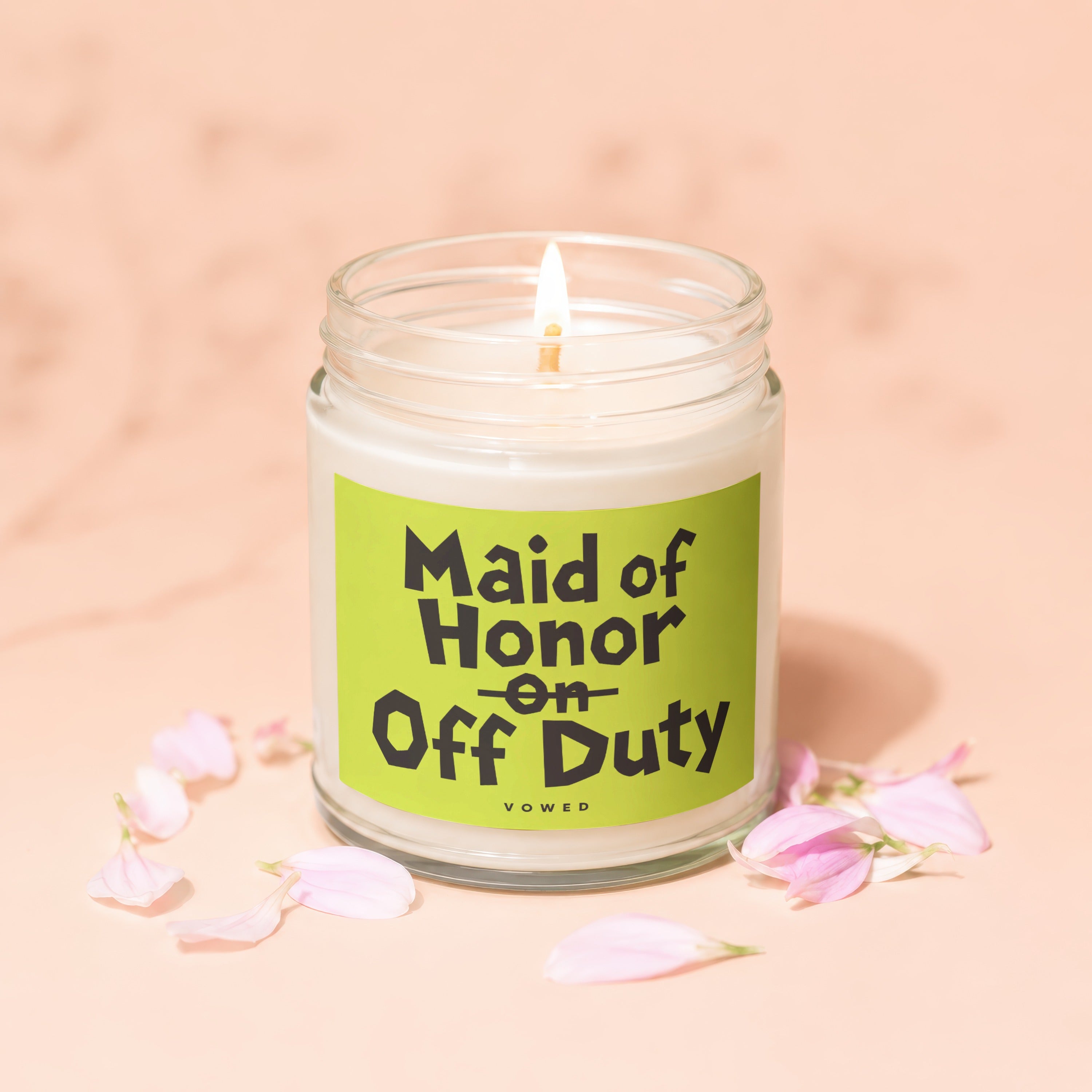 Lit candle in glass jar with "Maid of Honor on Off Duty" text and pink petals.