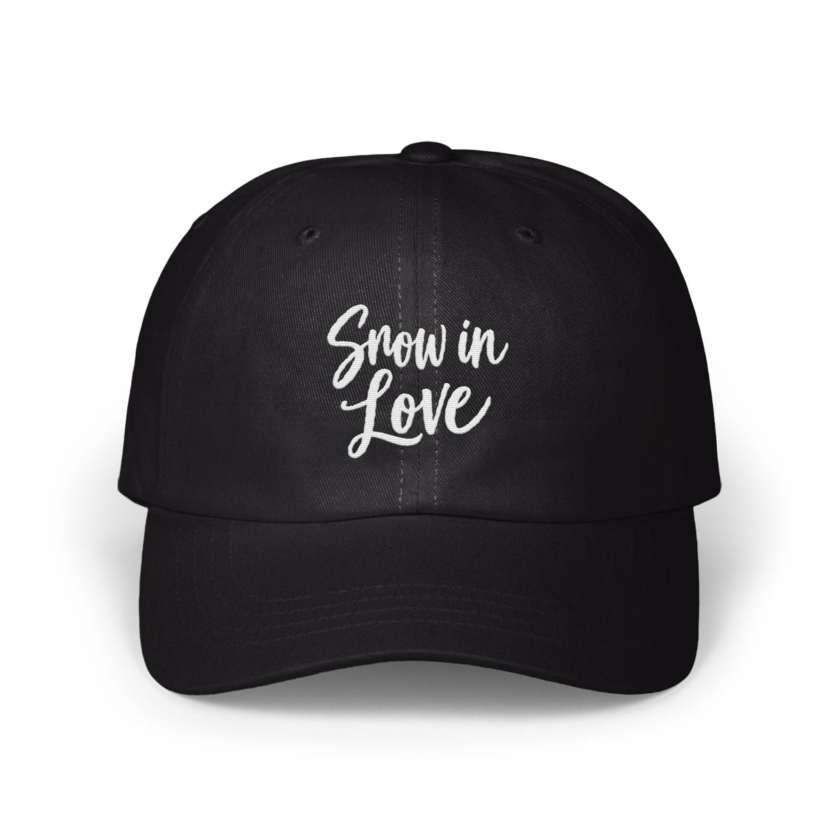 A black dad hat features the white embroidered text Snow in Love centered on the front panels.