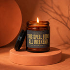 Amber jar candle with lit wick, reads "This Spell Took All Weekend".