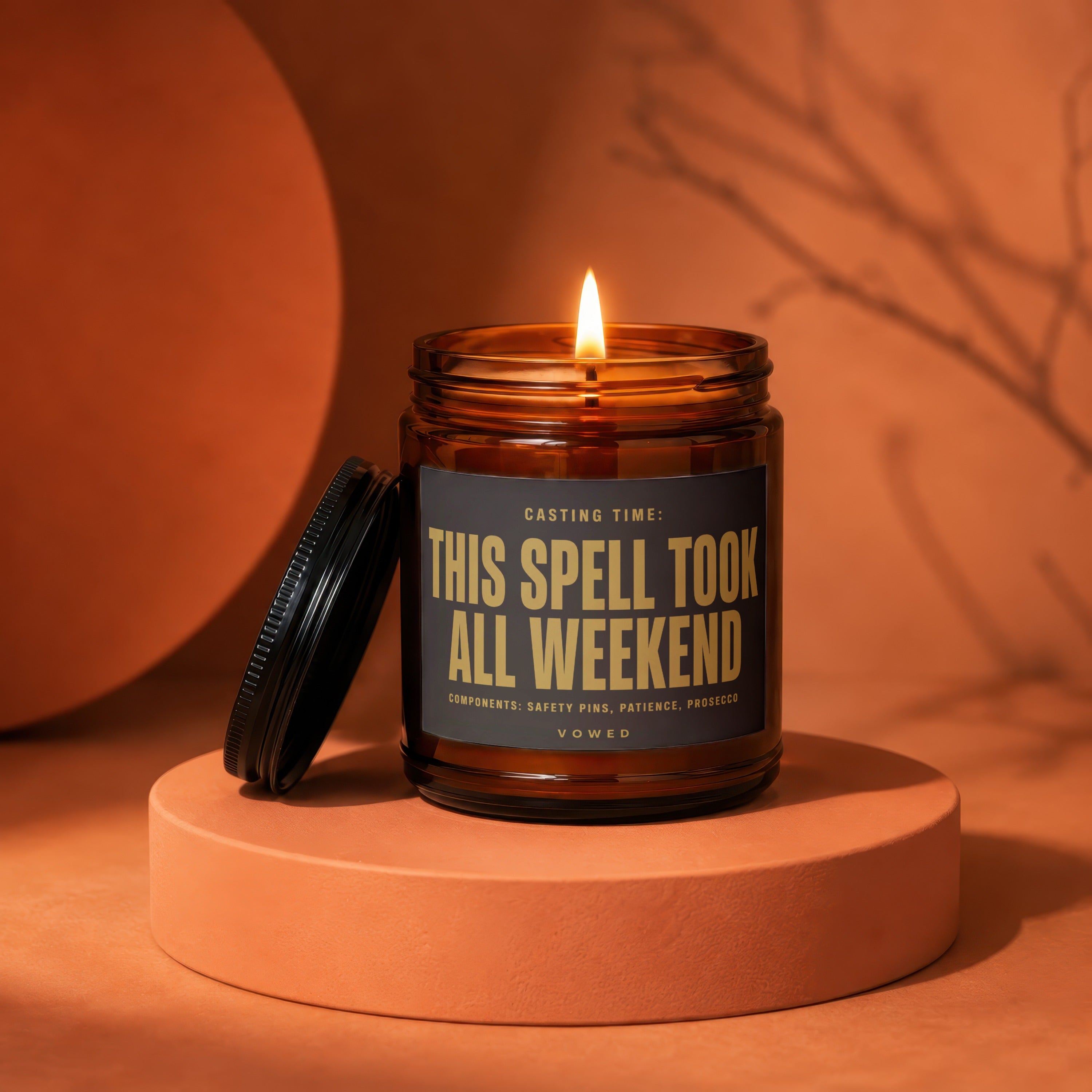 Amber jar candle with lit wick, reads "This Spell Took All Weekend".