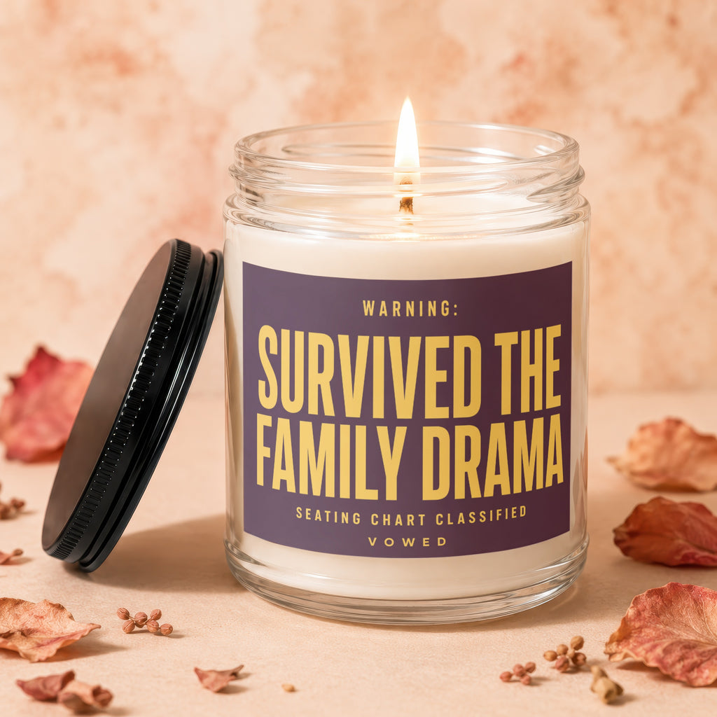 Glass candle with burning wick and label "WARNING: SURVIVED THE FAMILY DRAMA"
