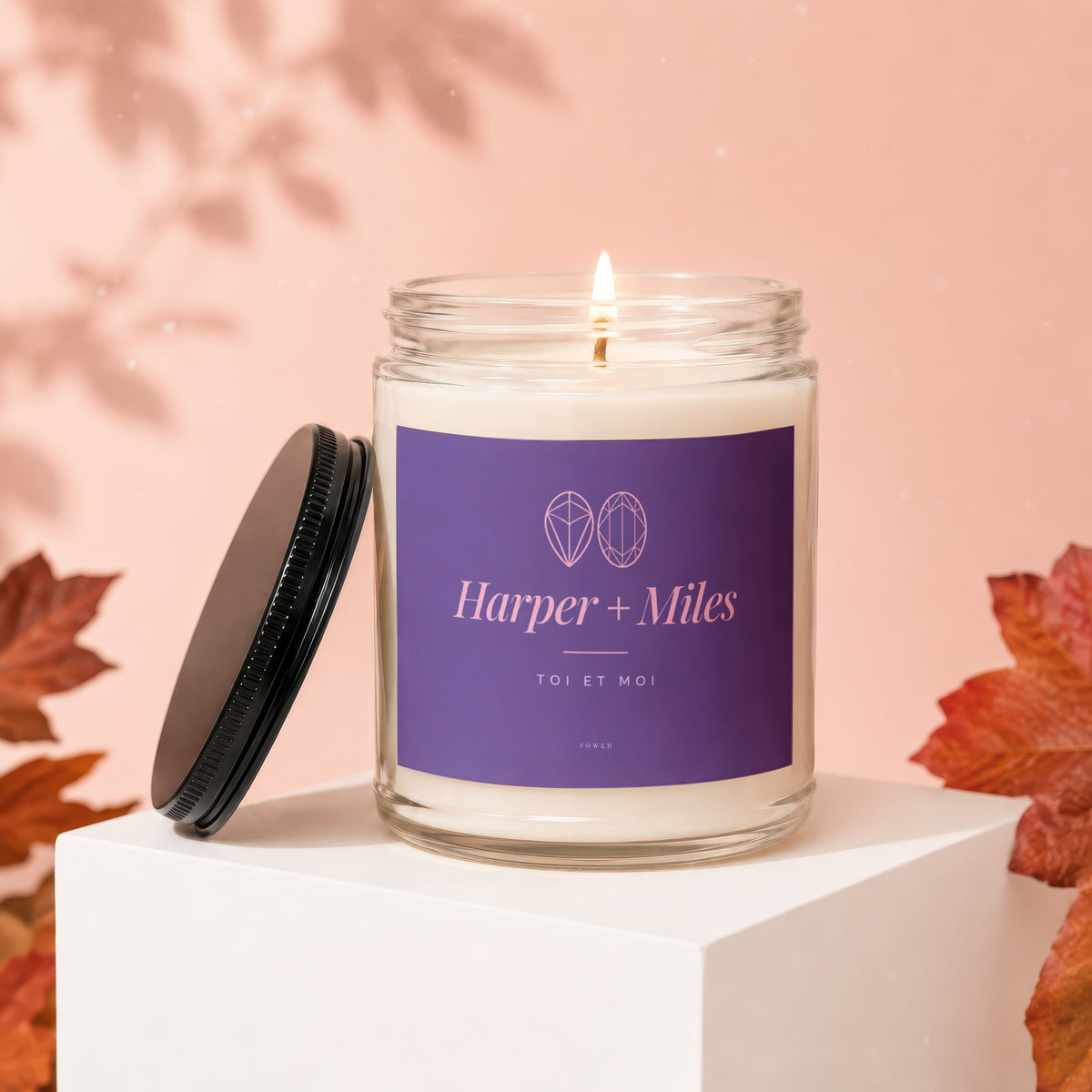 Harper + Miles candle with purple label, lit flame, and lid off.