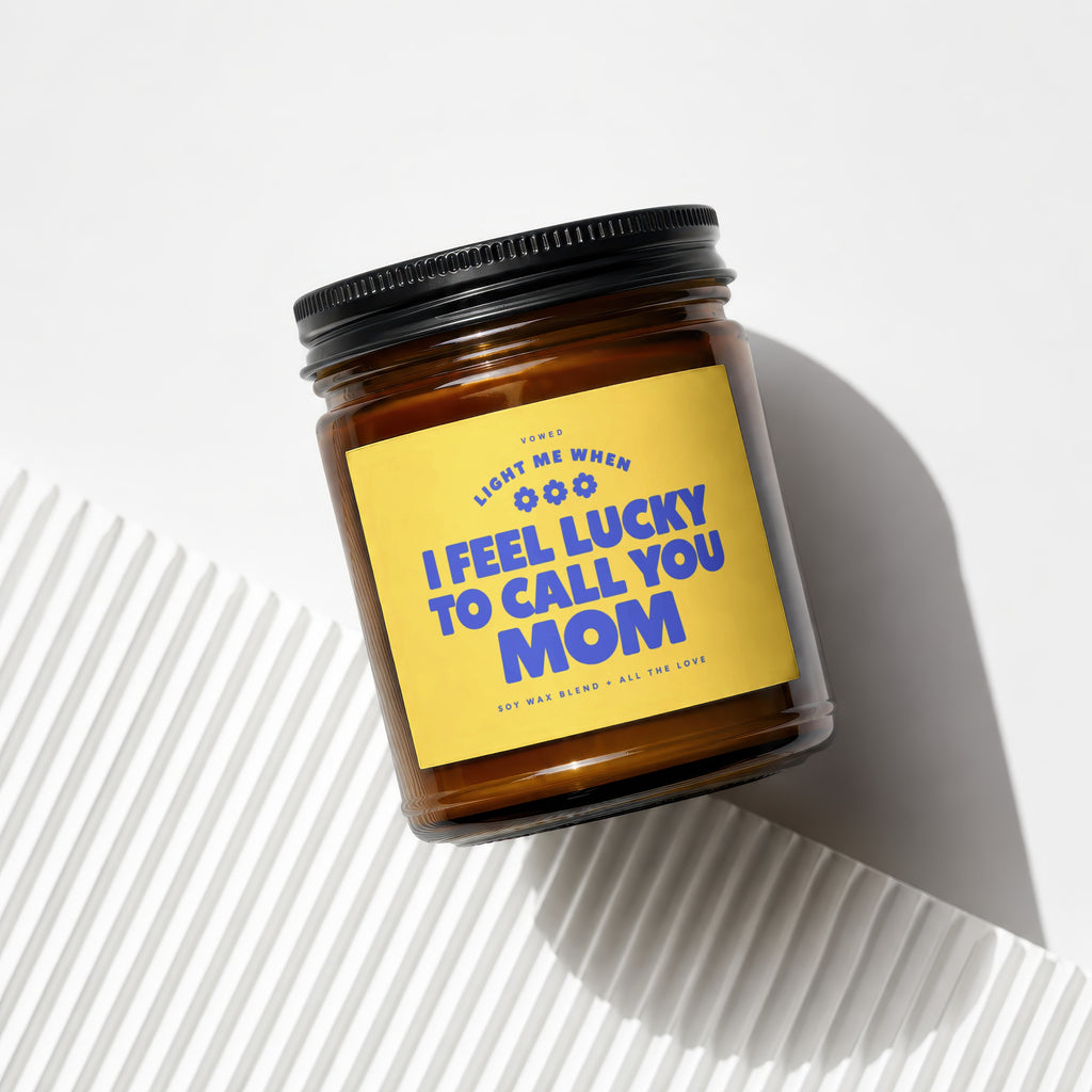 Amber glass candle with yellow label reading "I FEEL LUCKY TO CALL YOU MOM".