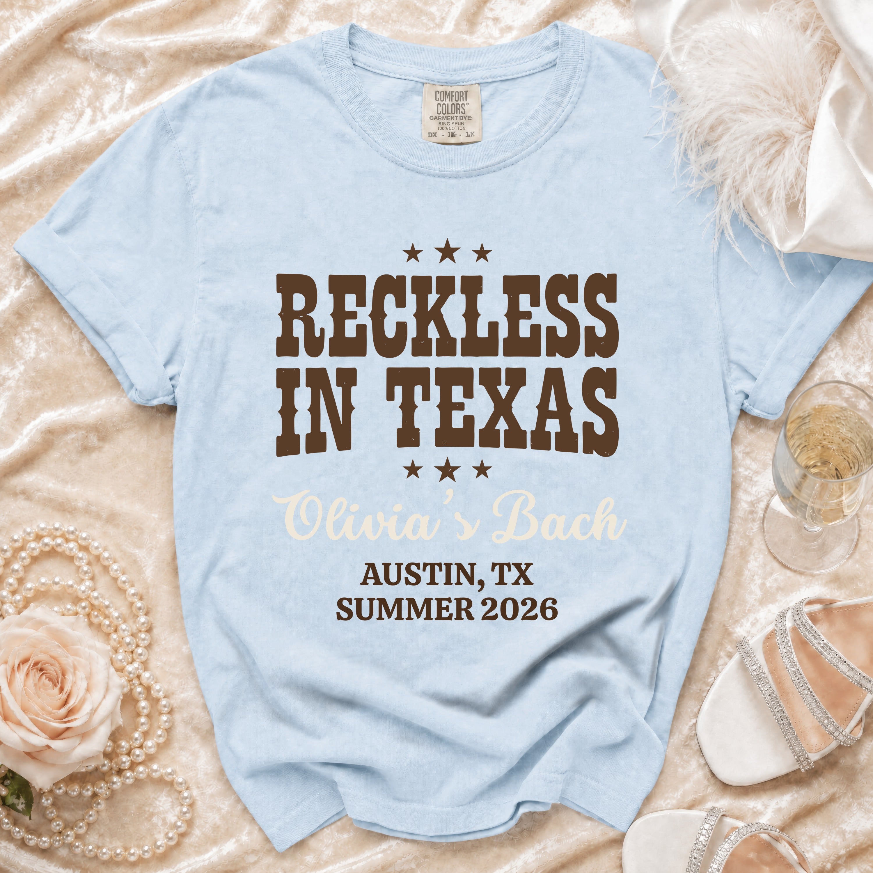 Light blue Comfort Colors t-shirt with "Reckless in Texas Olivia's Bach Austin, TX Summer 2026" text.