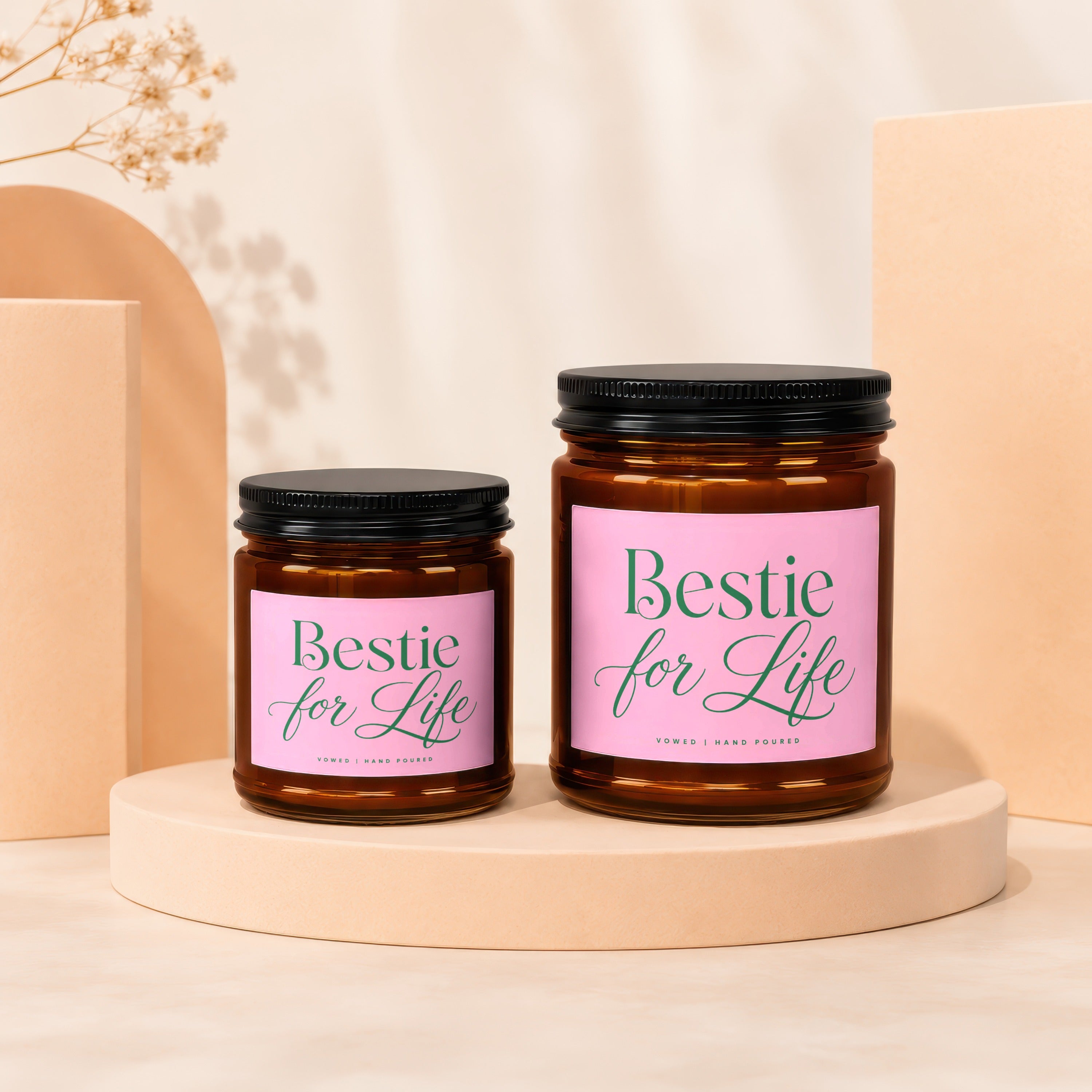 Two amber glass candles with pink labels reading "Bestie for Life" and "Vowed | Hand Poured".