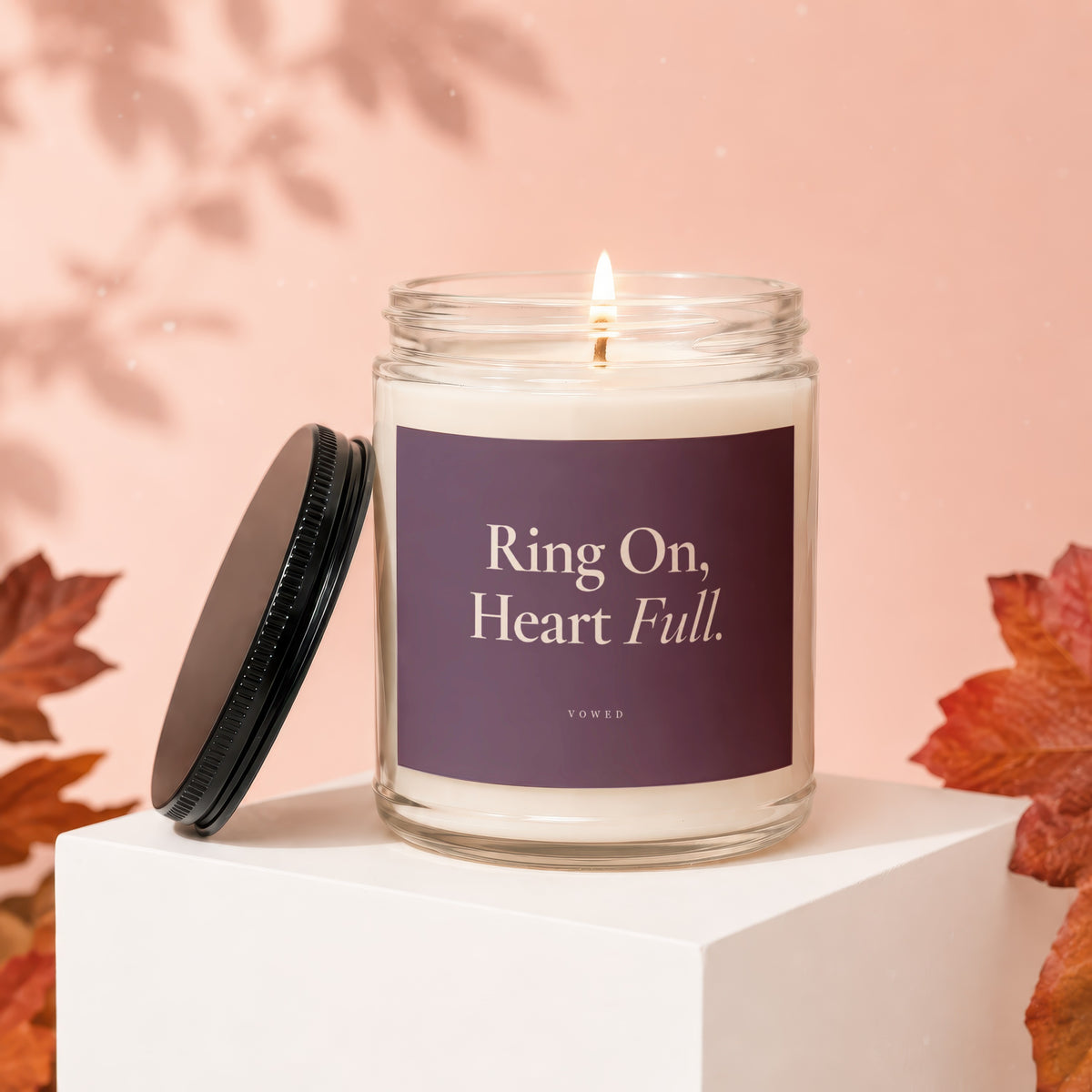 Lit candle in glass jar with purple label reading "Ring On, Heart Full."