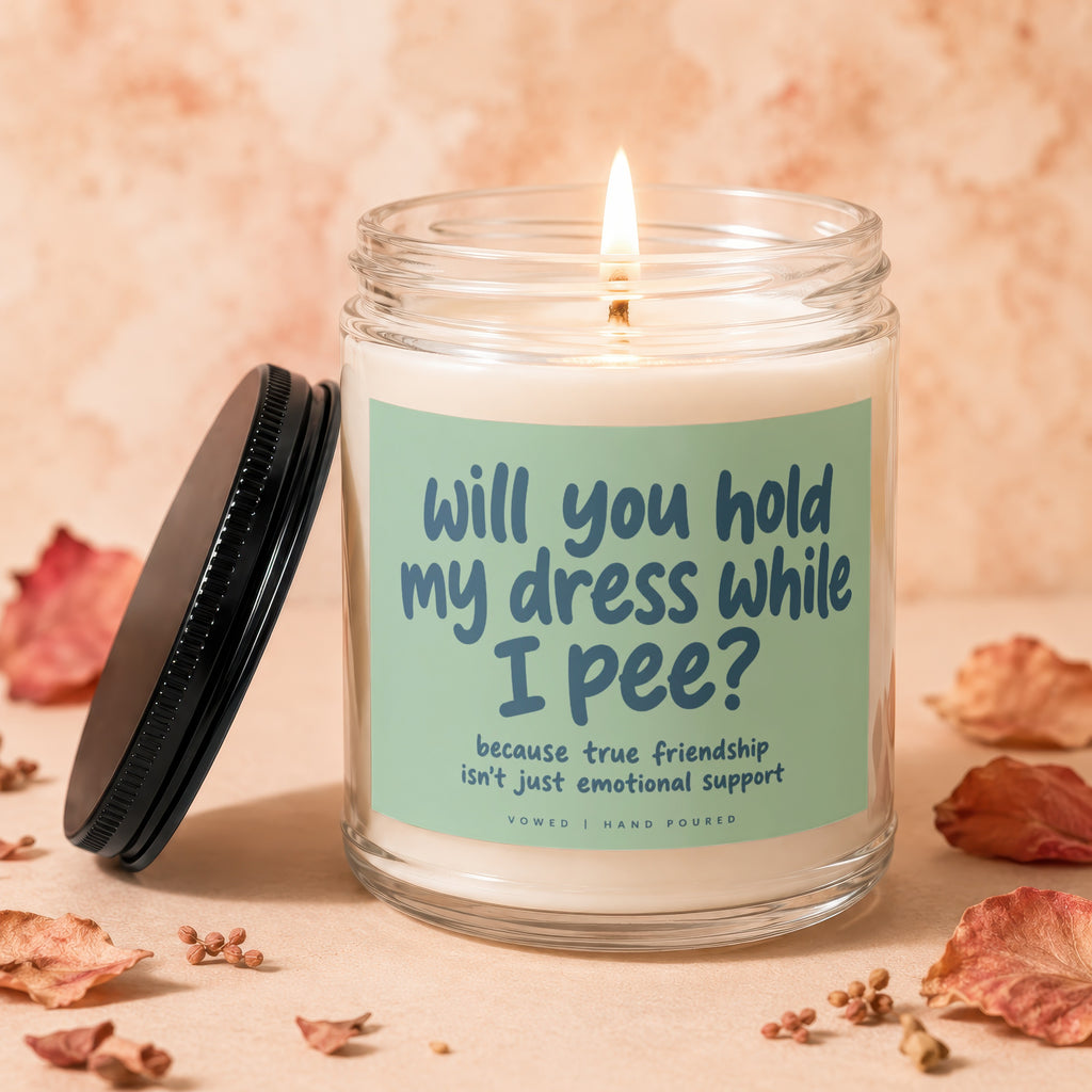 Candle with lit wick and "Will you hold my dress while I pee?" text.