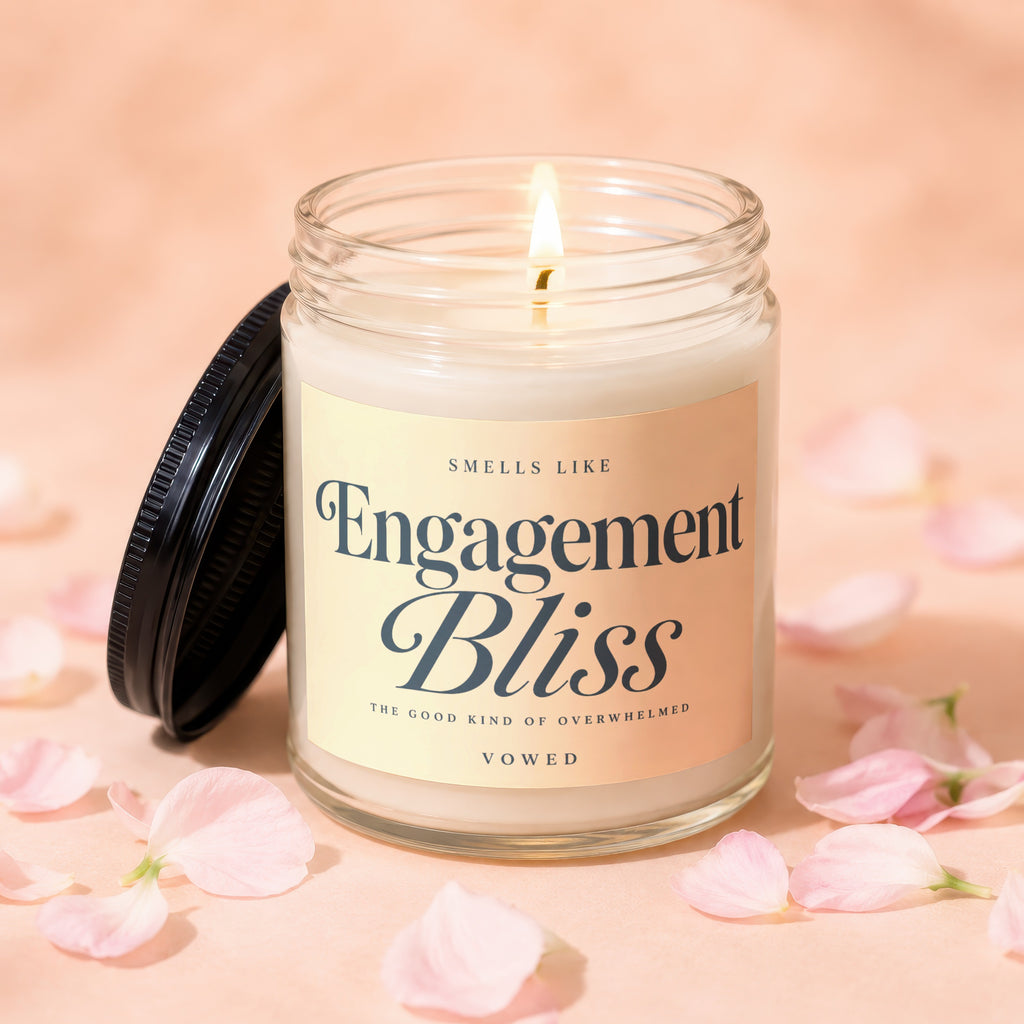Glass candle labeled "Engagement Bliss" surrounded by pink petals.