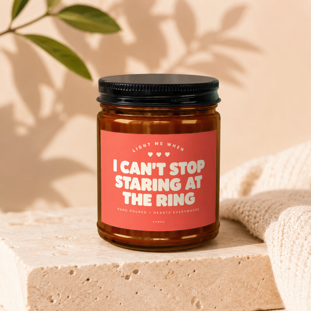 Amber candle with pink label reading "I Can't Stop Staring At The Ring".