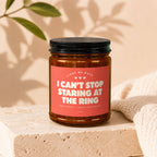 Amber candle with pink label reading "I Can't Stop Staring At The Ring".