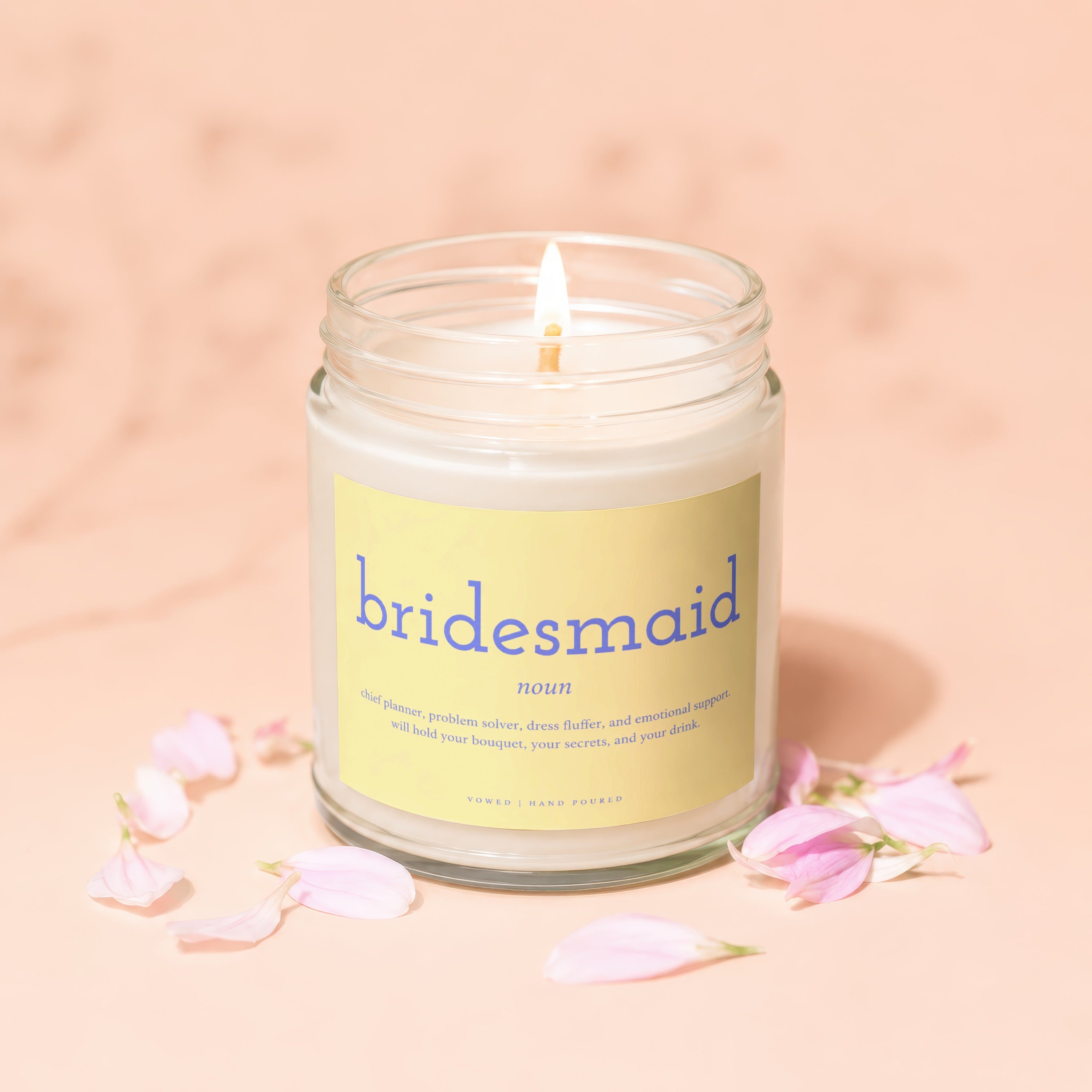 Bridesmaid definition candle, glass jar, lit wick, soft pink petals.