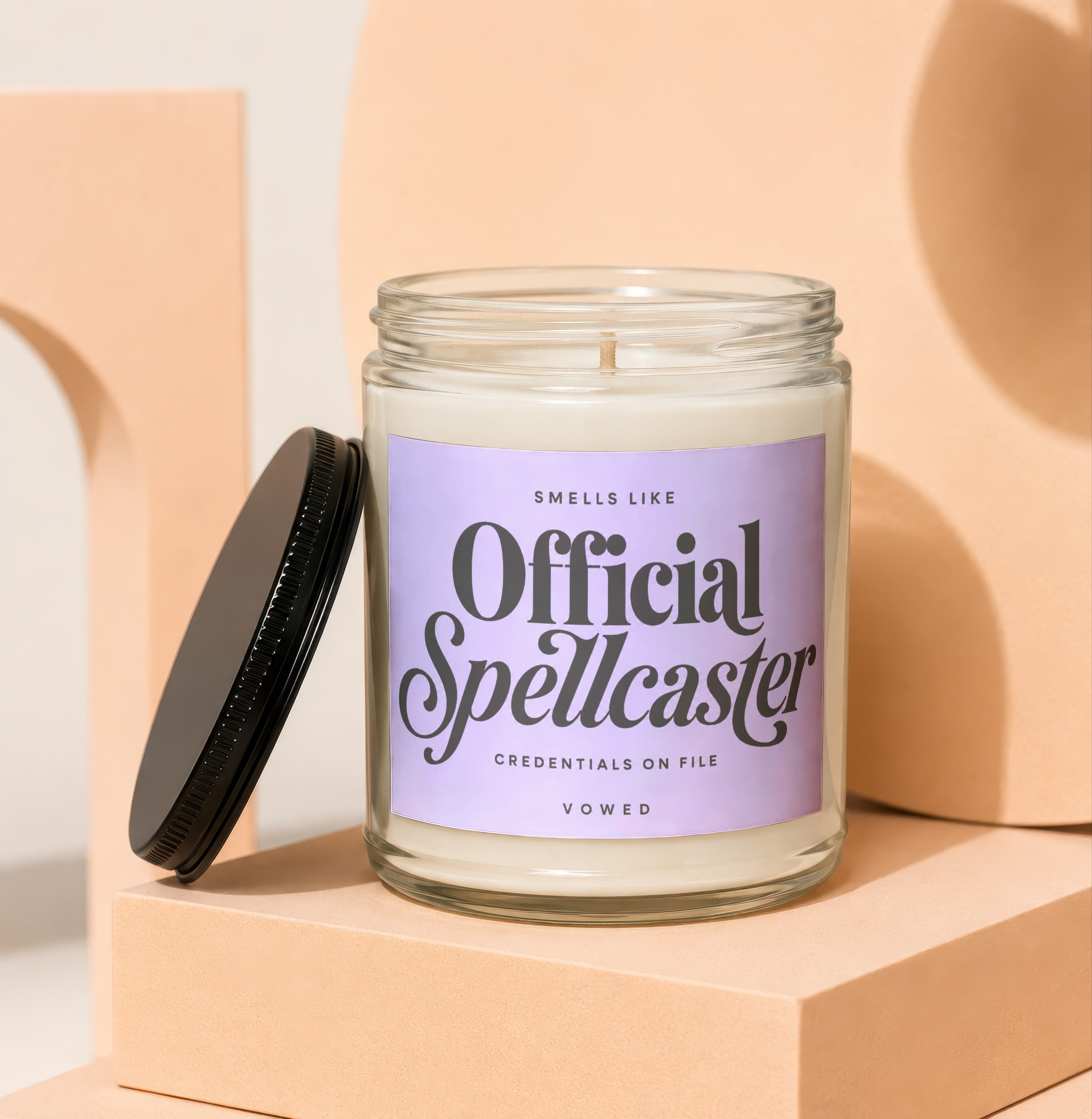 Candle with text "Smells Like Official Spellcaster Credentials On File Vowed".