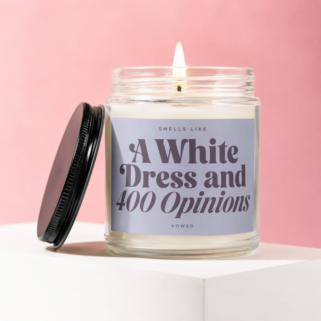Candle with label "Smells Like A White Dress and 400 Opinions" on pink background.