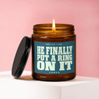 Lit candle in amber jar with label: "Smells Like He Finally Put A Ring On It Vowed".