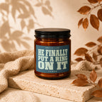 Candle with text "HE FINALLY PUT A RING ON IT" on blue label.