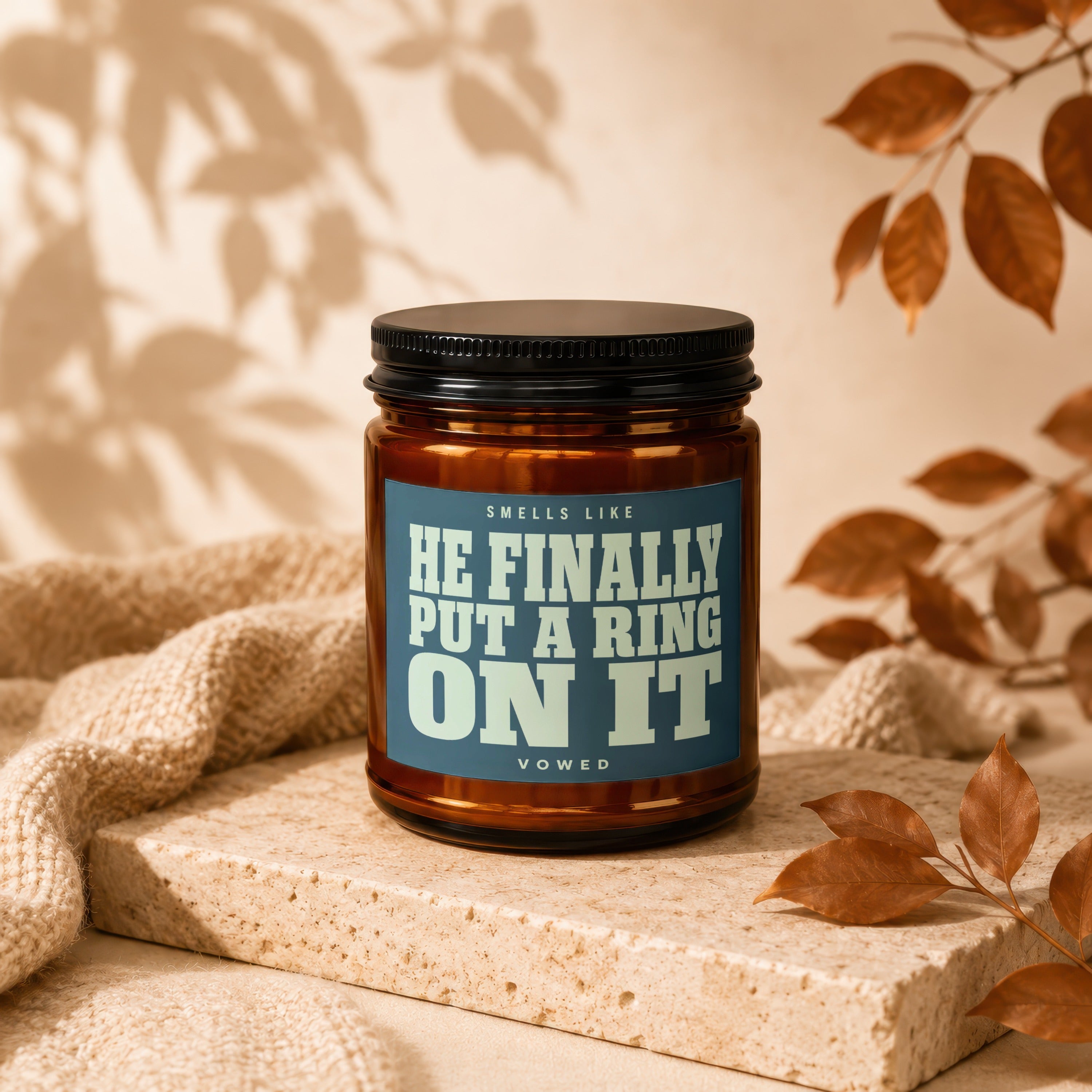 Candle with text "HE FINALLY PUT A RING ON IT" on blue label.