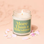 Candle with "More Than a Milestone" text under pink petals.