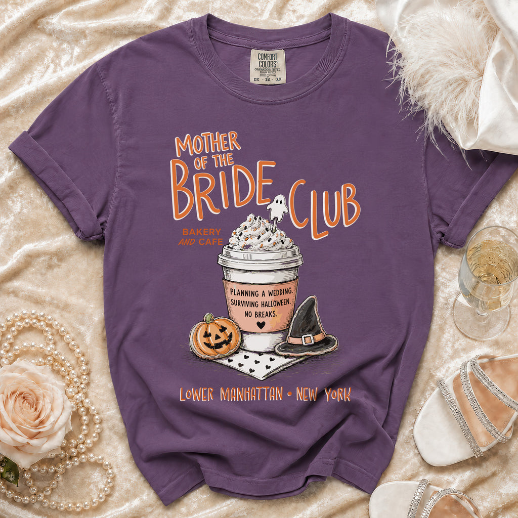 Purple t-shirt with "Mother of the Bride Club" text, coffee cup, pumpkin, and witch hat.