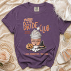 Purple t-shirt with "Mother of the Bride Club" text, coffee cup, pumpkin, and witch hat.