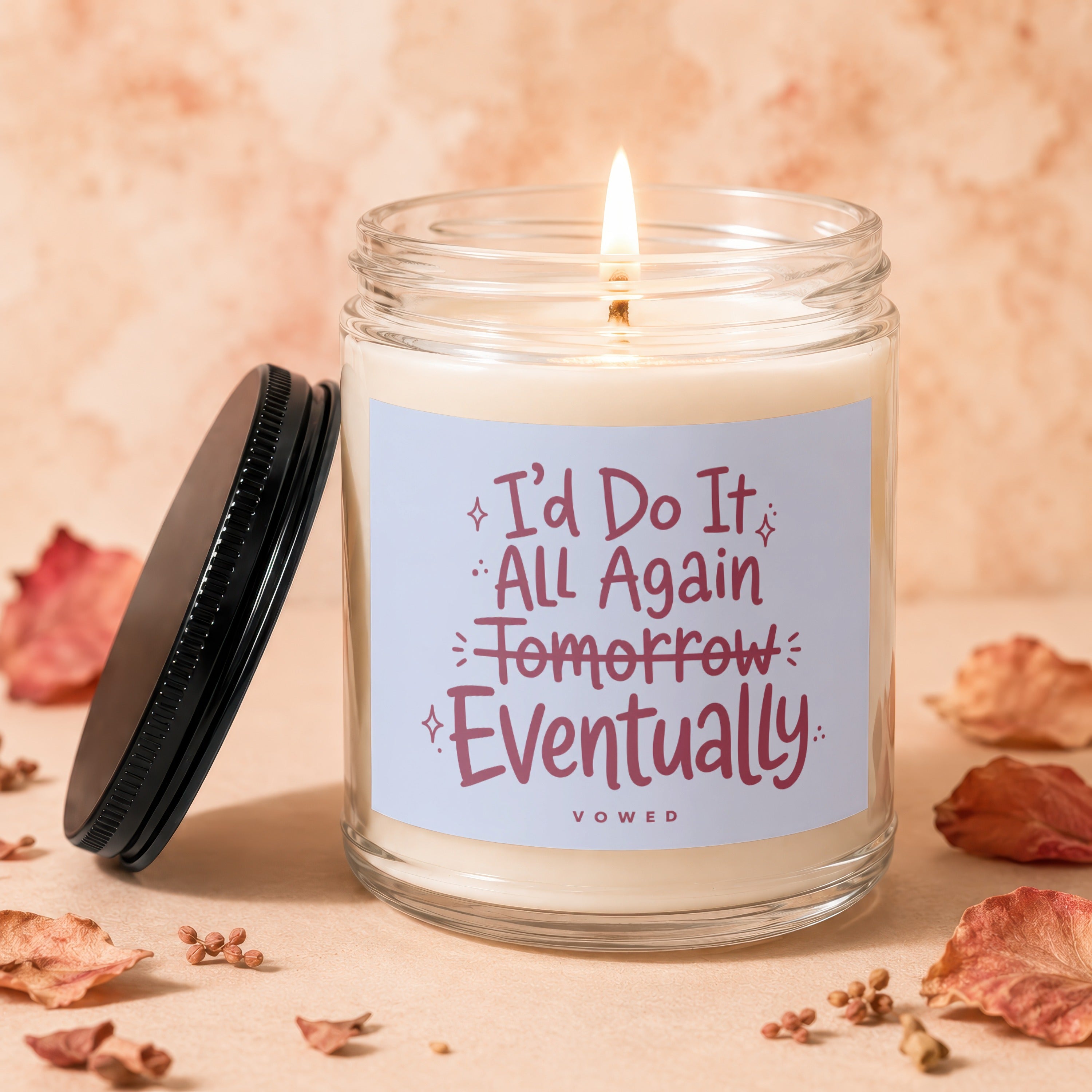 Candle with label "I'd Do It All Again Tomorrow Eventually" on a light peach background.