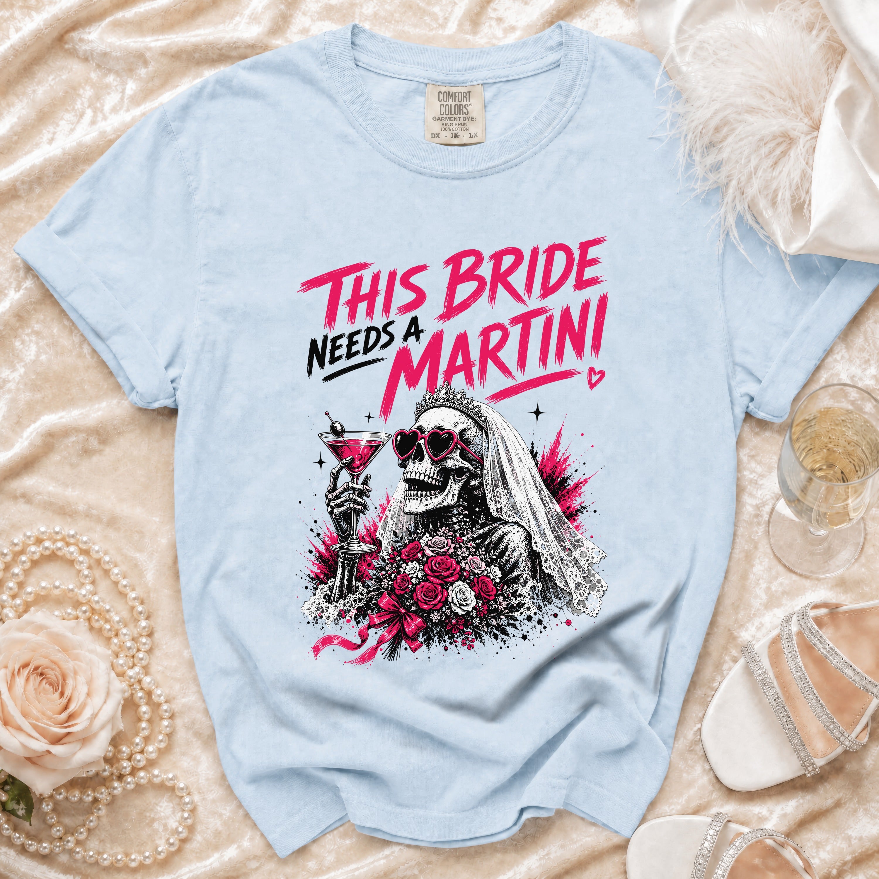 Light blue t-shirt with "This Bride Needs a Martini" graphic of a skeleton bride with a martini and roses.