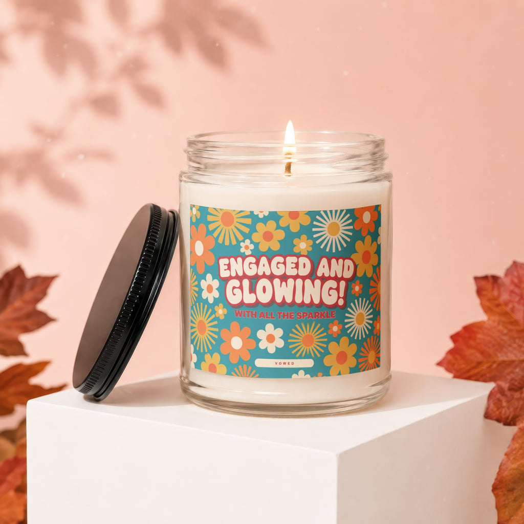 Candle with "Engaged and Glowing" text on a floral label, lid beside it.