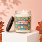 Candle with "Engaged and Glowing" text on a floral label, lid beside it.